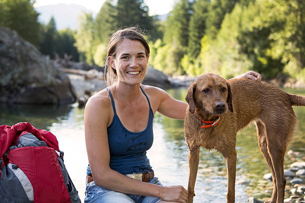 istock Hiker and Dog Sitting by a Stream in The Mountains. 527523608