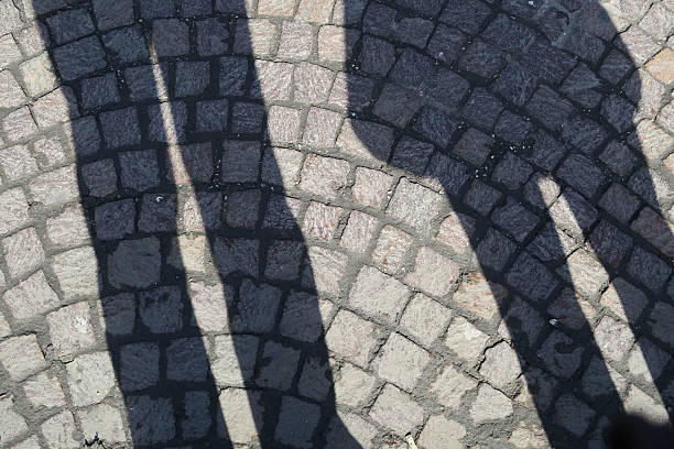 istock Peoples' shadows and on light colore cobblestones - cobble stones 527524892