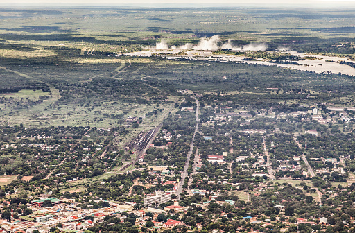 Aerial view of the Zambian city of Livingstone, showing features such as Livingstone railway station, and the Livingstone Museum (centre front), with the mist rising from Victoria Falls in the background, showing how the local name, Mosi-oa-Tunya (the Smoke that Thunders) is appropriate.