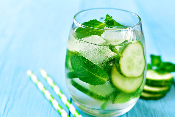 Homemade cucumber and mint lemonade. Homemade cucumber and mint lemonade in a glass on a blue wooden background. lime basil plant stock pictures, royalty-free photos & images