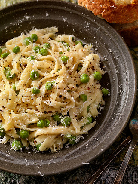 Creamy Fettucini with Peas and Parmesan Creamy Fettucini with Peas and Parmesan and crusty Bread -Photographed on Hasselblad H3-22mb Camera cooked selective focus vertical pasta stock pictures, royalty-free photos & images