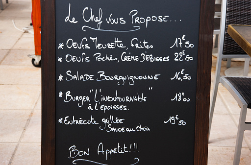 Handwritten Menu board  in white chalk on black background with daily specials from the traditional Burgundy dishes and prices in Dijon, France.