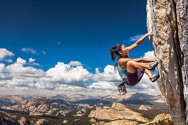 Rock climber clinging to a cliff. Female climber dangles from the edge of a challenging cliff. adrenaline stock pictures, royalty-free photos & images