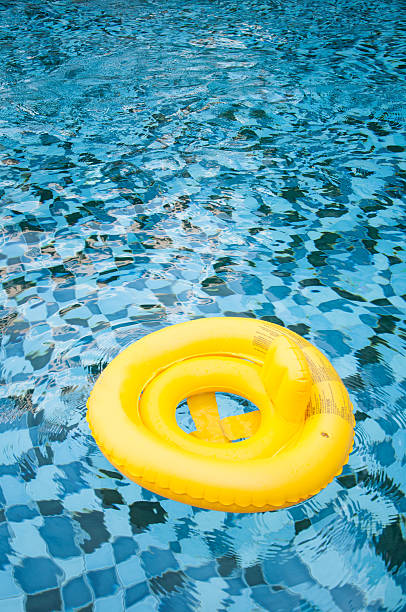 istock floating yellow ring on blue water swimpool with waves reflectin 527533508