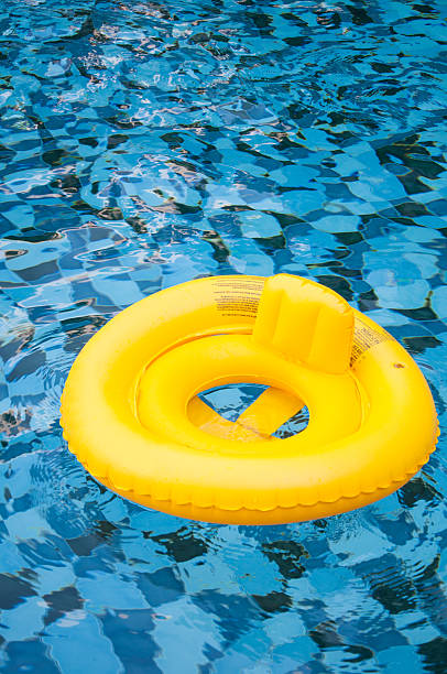 istock floating yellow ring on blue water swimpool with waves reflectin 527533572