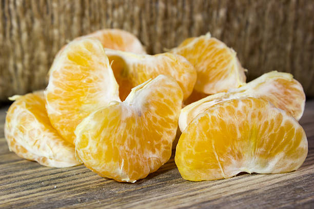 istock Mandarin slices on wooden background 527536962