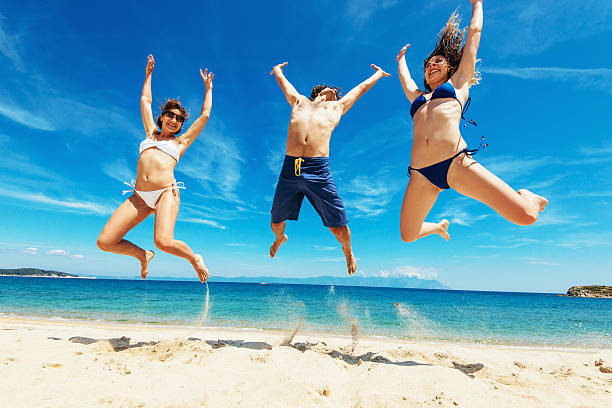 istock People having fun at beach in summer, jumping on sand 527542236