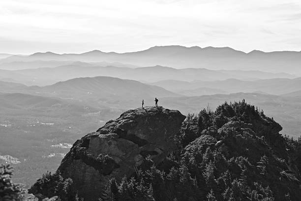 Black and white image showing two hikers sharing a beautiful moment atop Grandfather Mountain in the Blue Ridge Mountains of North Carolina