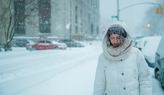 Teenager girl walks under snowfall at the street in Manhattan, New York City, NY, during the snowstorm Jonas