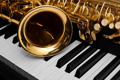  Fragment of a saxophone lying on a piano keyboard 