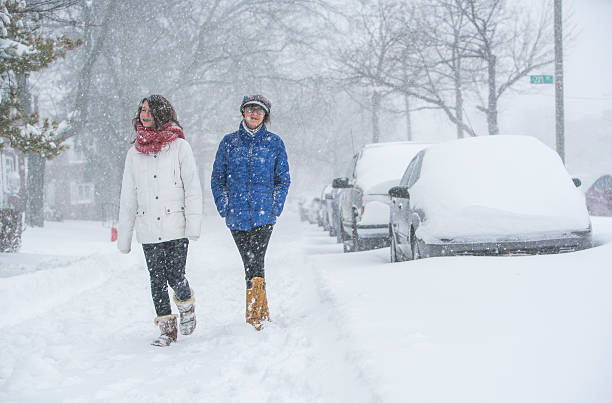 zwei teenager-mädchen unter schneefall auf der straße - queens head stock-fotos und bilder