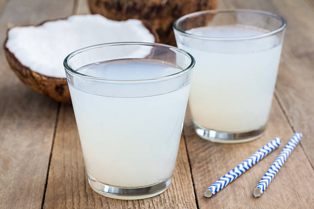 Coconut drink with pulp in glass on wooden table stock photo