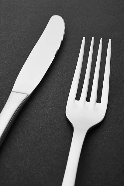 istock Knife and fork detail over a black background. Cutlery 527545816