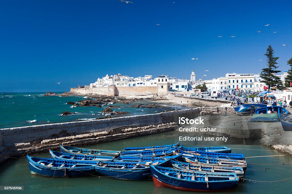 Essaouira, Morocco Essaouira, Morocco - June 21, 2012: Blue boats and unidentified people in the harbour of Essaouira. It is a famous tourist destination in Morocco. Essaouira Stock Photo