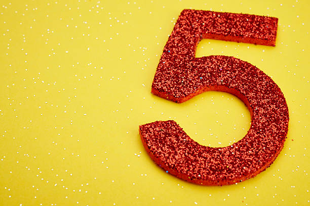istock Number five red color over a yellow background. Anniversary 527545968