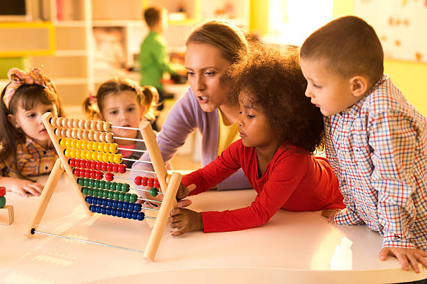 istock Children and teacher counting with abacus at preschool. 527551404