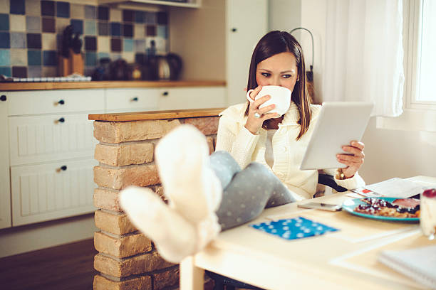 istock Young woman reading tablet and having breakfast in the kitchen 527554775