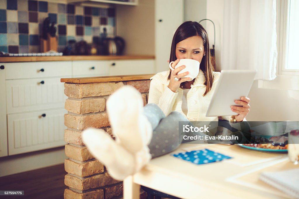 Young woman reading tablet and having breakfast in the kitchen Winter Stock Photo