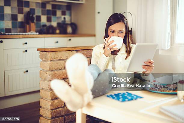 Young Woman Reading Tablet And Having Breakfast In The Kitchen Stock Photo - Download Image Now