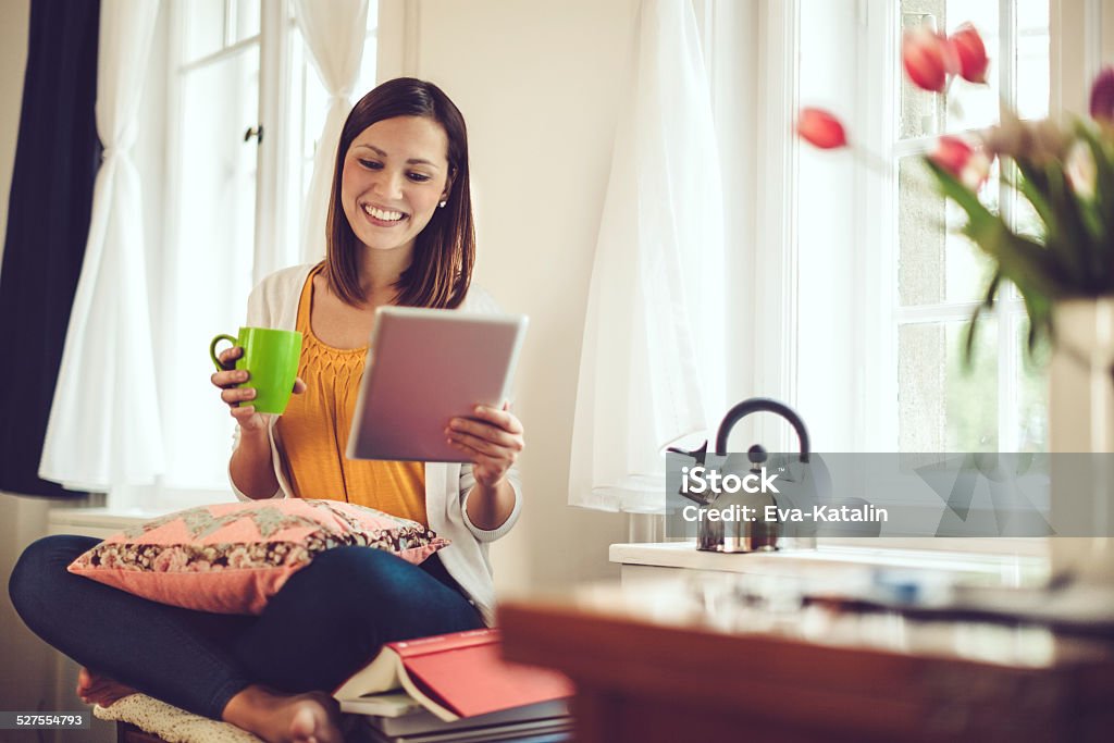 Smiling woman reading her tablet at home Springtime Stock Photo