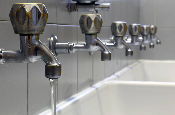 one tap with water and many taps shut and a ceramic washbasin