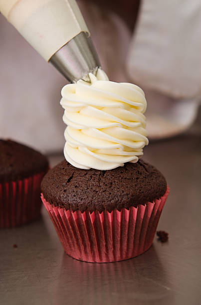 istock Whipped cream frosting being put on a cupcake 527556231