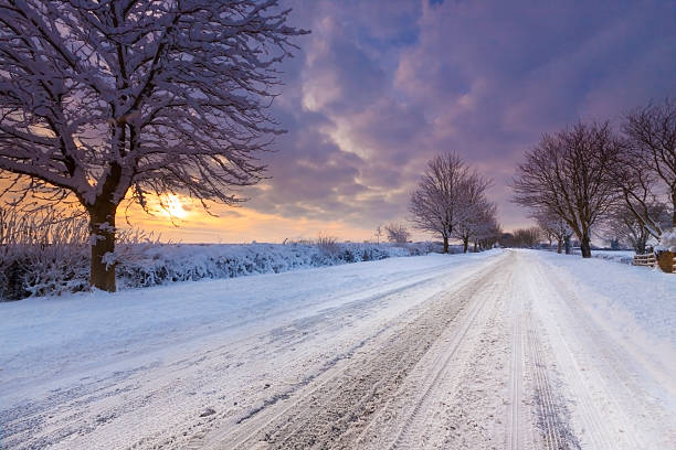 Deep snow covers the countryside in Oxfordshire. Vehicles have left track marks stretching into the distance