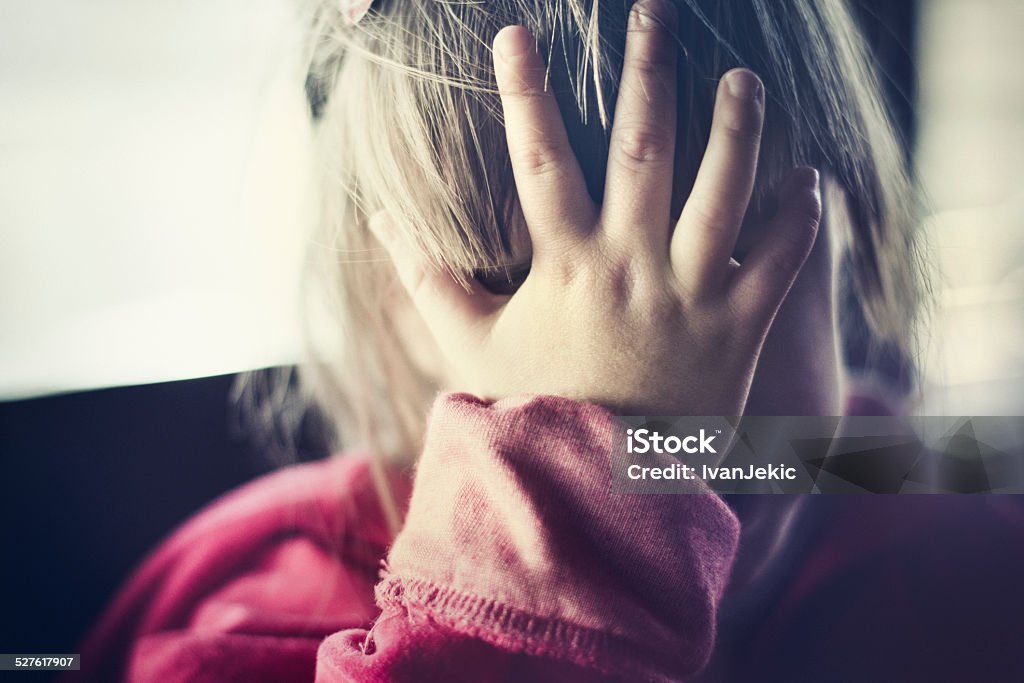 Child sadness and disbelief Sad little girl covered her face with hand. In reality, this is a joyful and happy little child. :) Toned image, rich in tones, slight grain added for texture, AdobeRGB profile. Child Abuse Stock Photo