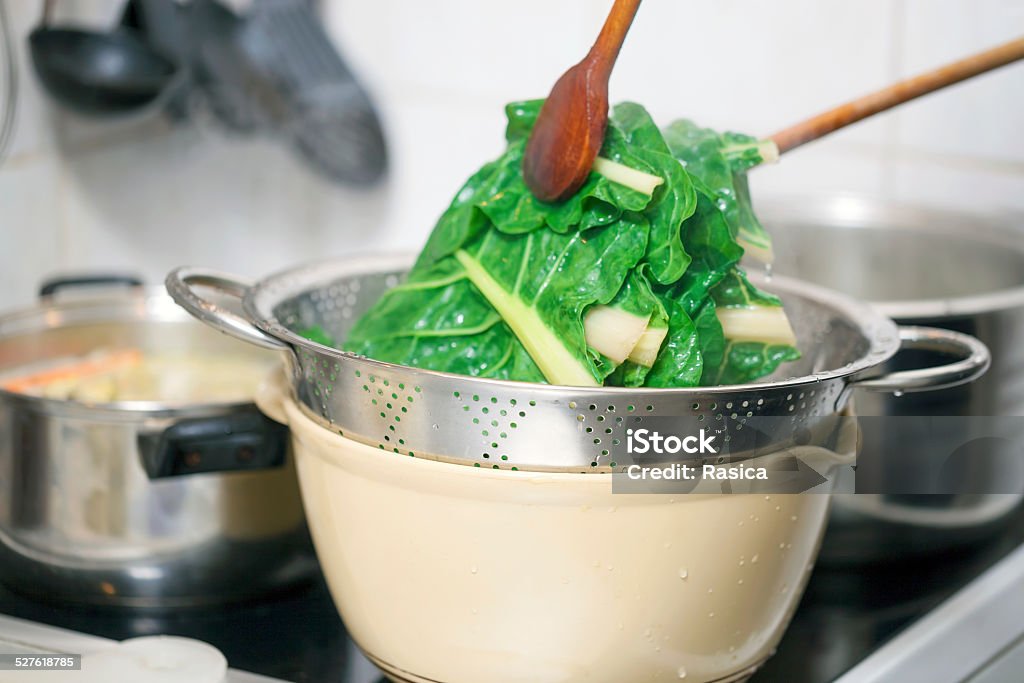 Blanching hot chard using kitchenware Preparing healthy lunch in the kitchen, blanching chard using kitchen utensils Boiling Stock Photo