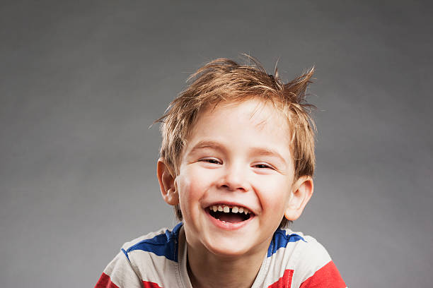 istock Young boy laughing against gray background, portrait 527634023