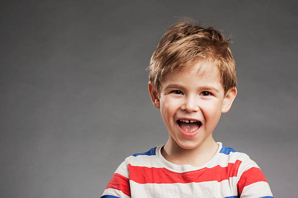 istock Young boy laughing against gray background, portrait 527634027