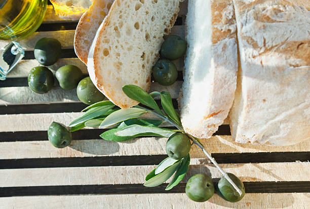 Italy, Tuscany, Magliano, Close up of bread, olives and olive oil on chopping board, elevated view