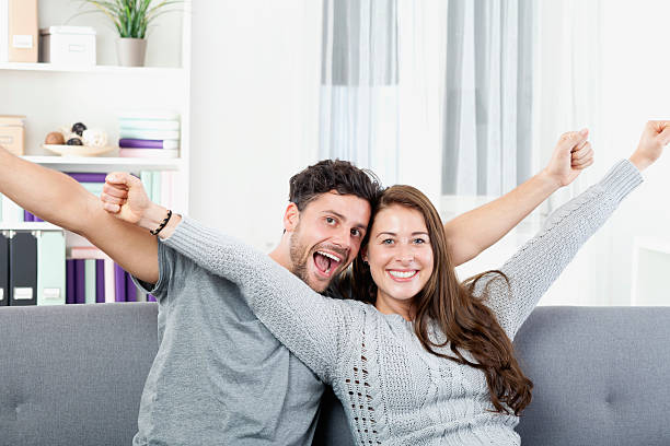 istock Cheerful young couple sitting on sofa, arms out 527635439