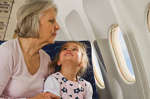 Senior woman and girl looking through window  on airplane stock photo