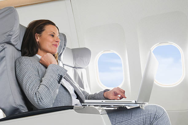 Businesswoman using laptop on airplane stock photo