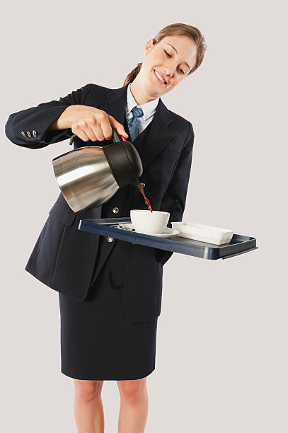 Young air hostess pouring hot beverage