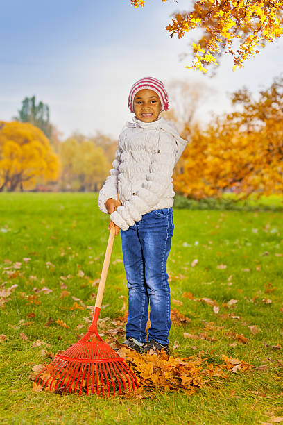 istock African girl working with red rake in park alone 527655445