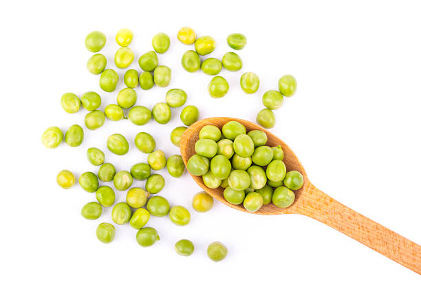 istock Green peas in a wooden spoon on a white background. 527660169