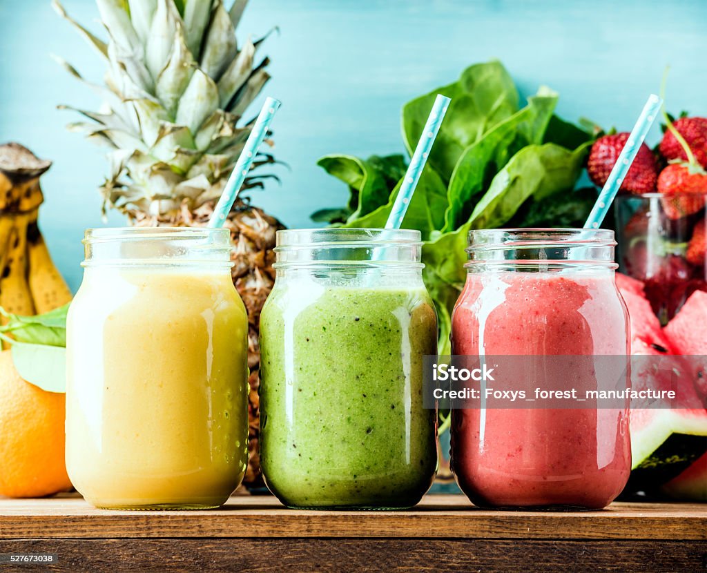 Freshly blended fruit smoothies of various colors and tastes Freshly blended fruit smoothies of various colors and tastes  in glass jars. Yellow, red, green. Turquoise blue background Smoothie Stock Photo