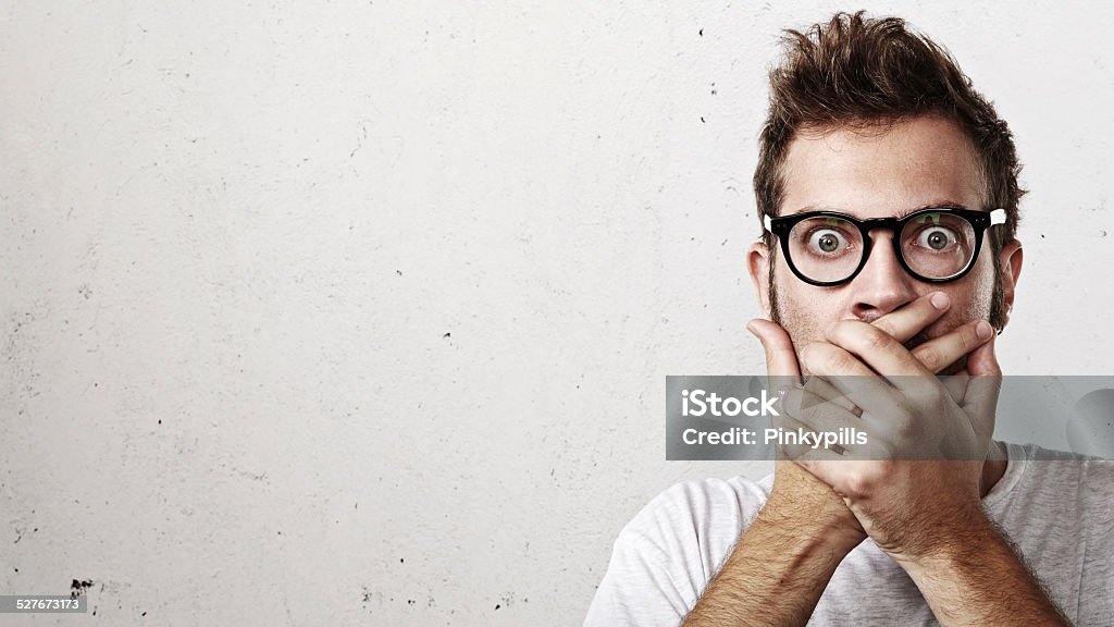 Shocked man covering his mouth with hands Portrait of a surprised young man wearing eyeglasses Eye Stock Photo