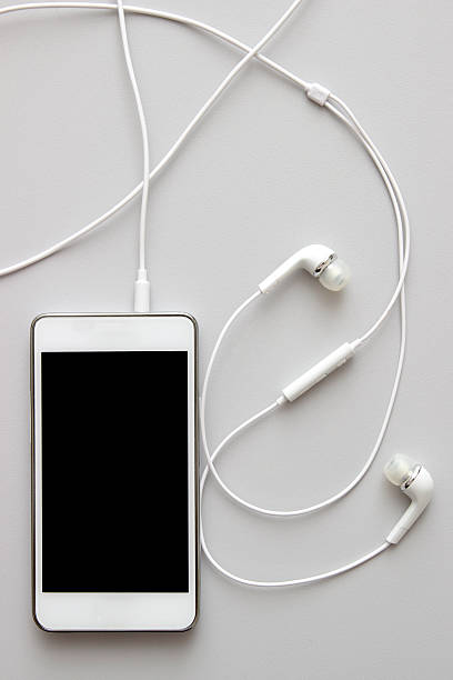 istock White smart phone with earphones and isolated screen on table 527673551