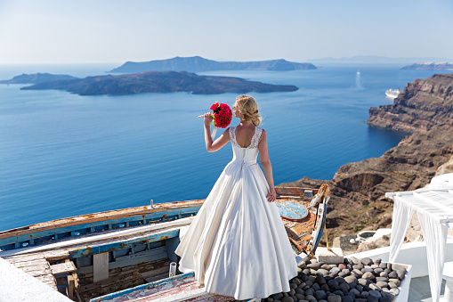 Bride with a bouquet of flowers looking out to the sea