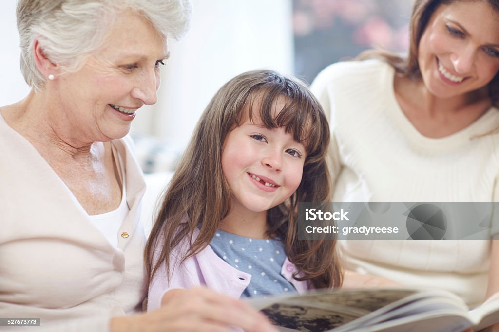 I love reading books Shot of a three generational family sitting and reading together at home 30-39 Years Stock Photo