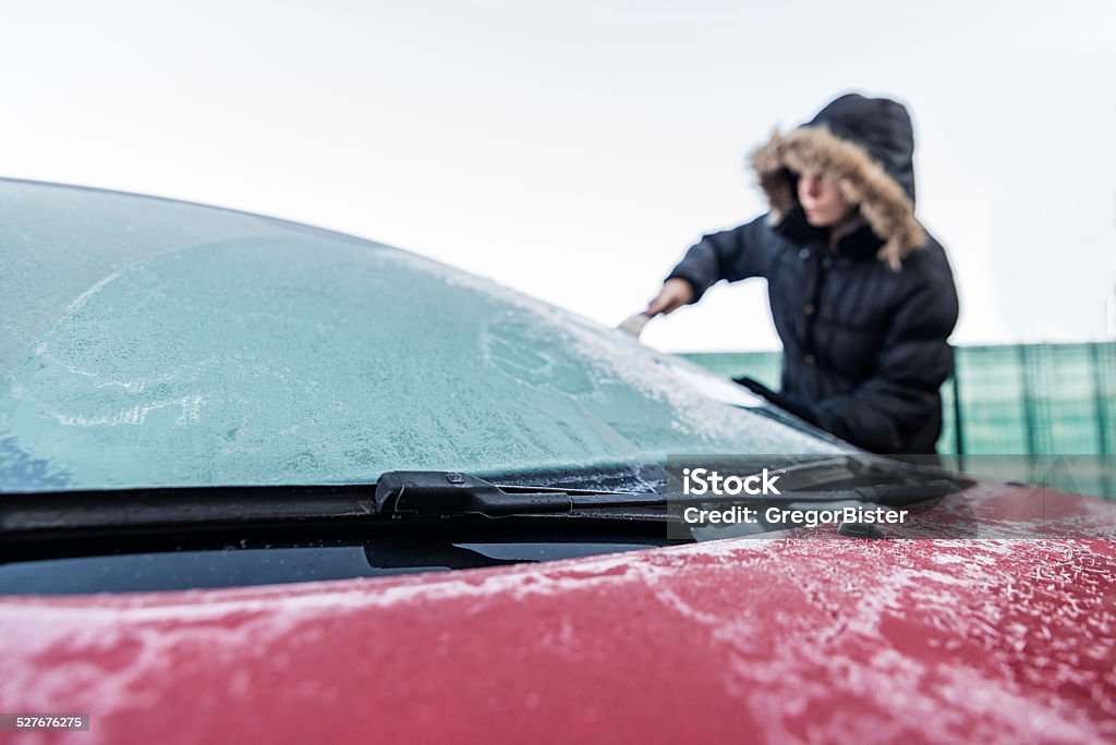Woman scraping ice from car windscreen Woman scraping ice from car windscreen  Car Stock Photo