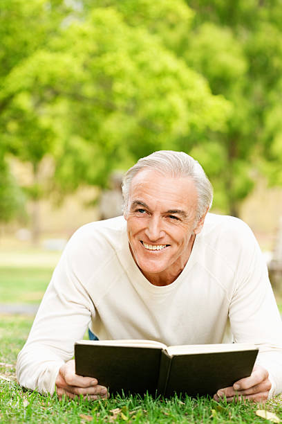 istock Senior Man Reading In The Grass 527676463