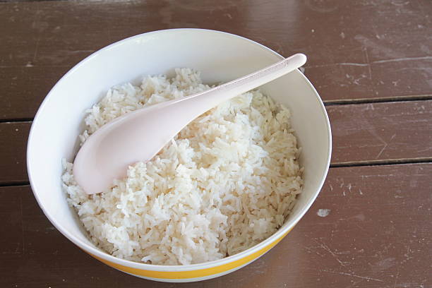 bowl of boiled rice with ladle on wood table