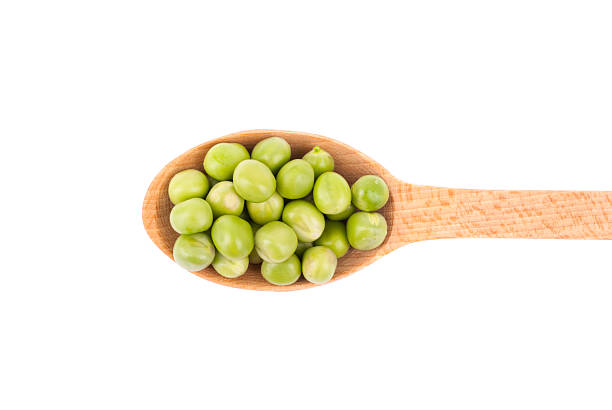 istock Green peas in a wooden spoon on a white background. 527677159