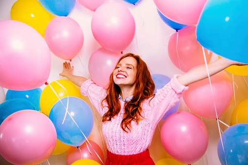 Young woman enjoys many balloons surrounding her