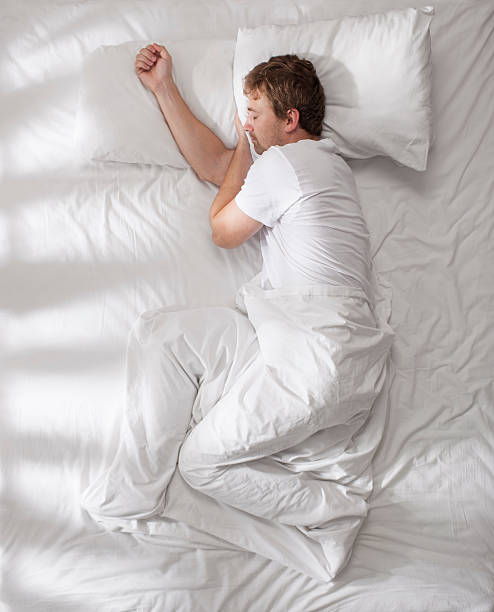 Sleeping young man. Young man sleeping in bed, photo from above. lying on side stock pictures, royalty-free photos & images