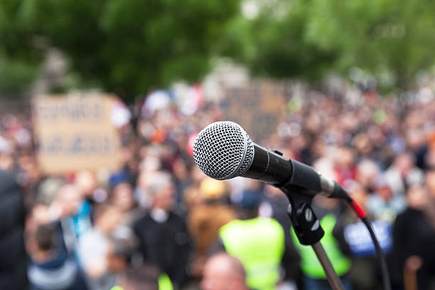 Political protest. Public demonstration. Microphone. Microphone in focus against blurred crowd. Political rally. political rally stock pictures, royalty-free photos & images